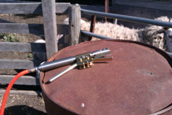Gas detailer (hot knife) resting on an oil drum