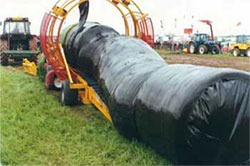 Grassy paddock with large sausage shaped plastic bales