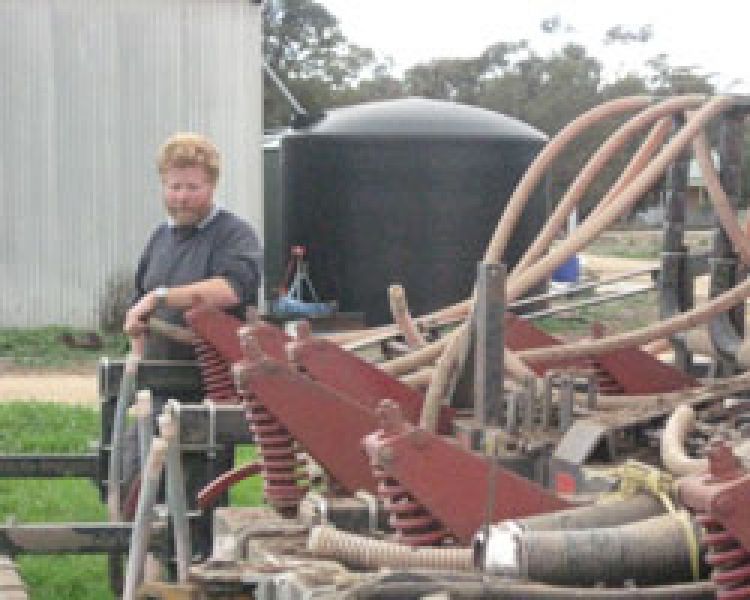 Farmer (Peter Teasdale) leaning on machinery at his farm 