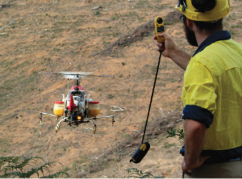 Man in field operating an unmanned helicopter for aerial spraying 