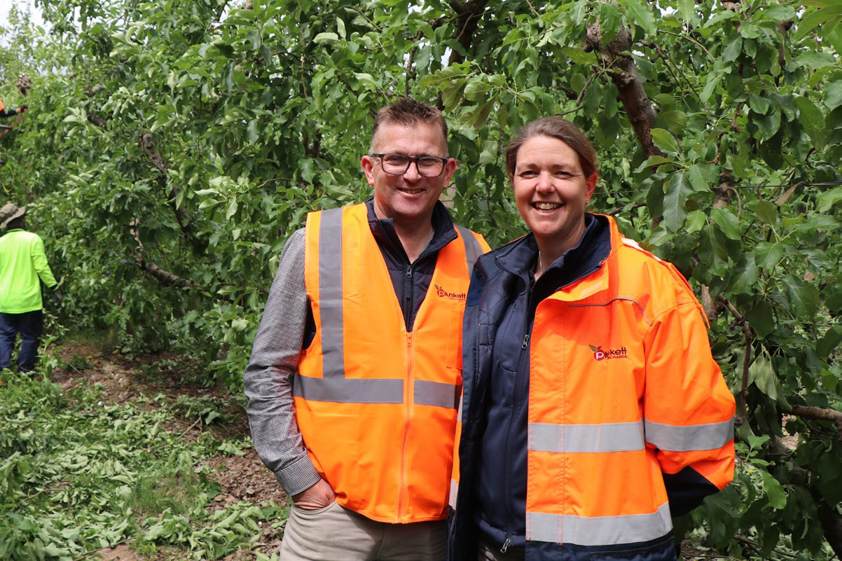Danny and Jess standing in front of orchard