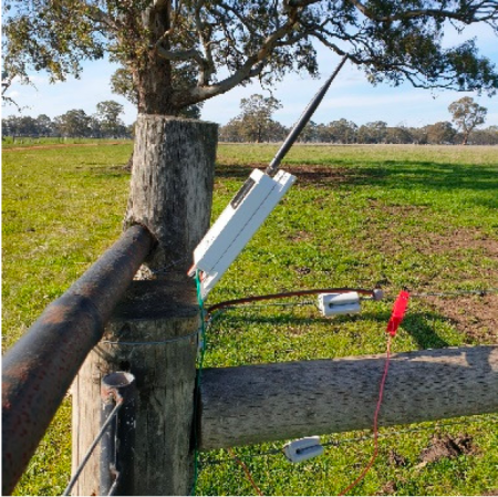 Device attached to wooden post of fence to monitor voltage