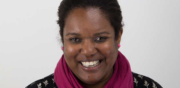 Patricia Adjei wearing pink scarf and black top smiling at the camera,