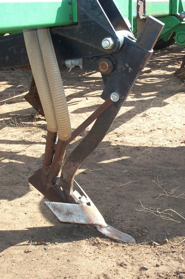 Close-up of a chisel point with wide sweep, with seed and fertiliser chutes behind.