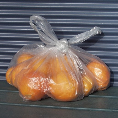 Oranges tied up in a plastic bag on an outdoor table