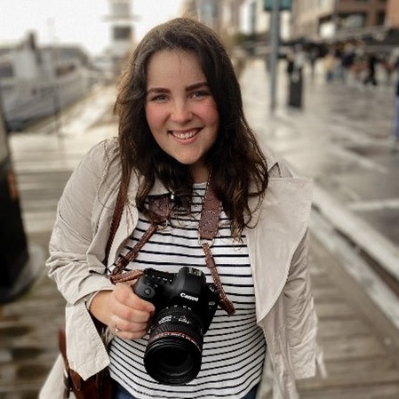 A woman smiling holding a camera