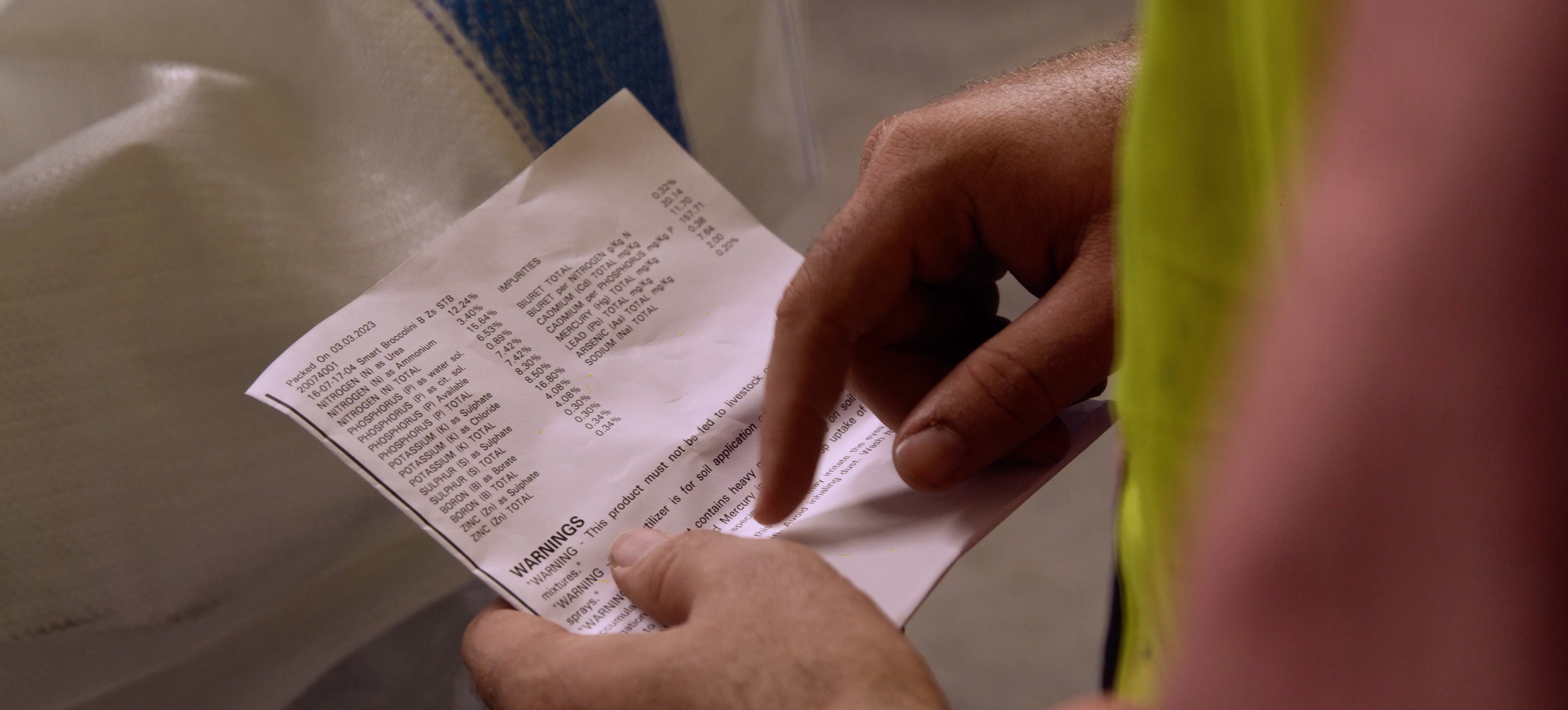 Close up photo of a person reading fertiliser label.
