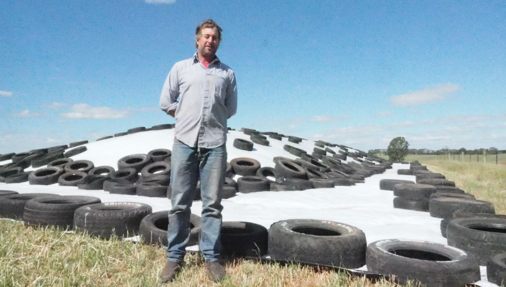 Farmer Andrew Edgar standing in front of a pile of silage covered by tyres