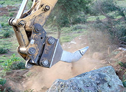 Ripper attached to a bulldozer digging into brown earth