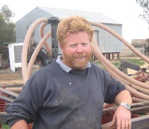 Farmer (Peter Teasdale) leaning on machinery at his farm 