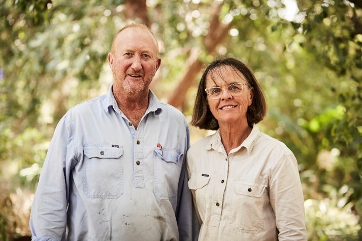 Sheep and wool producers Jo and Greg Bear. Image: Woolmark (https://www.woolmark.com/) Photo of Jo and Greg Bear against a background of trees.