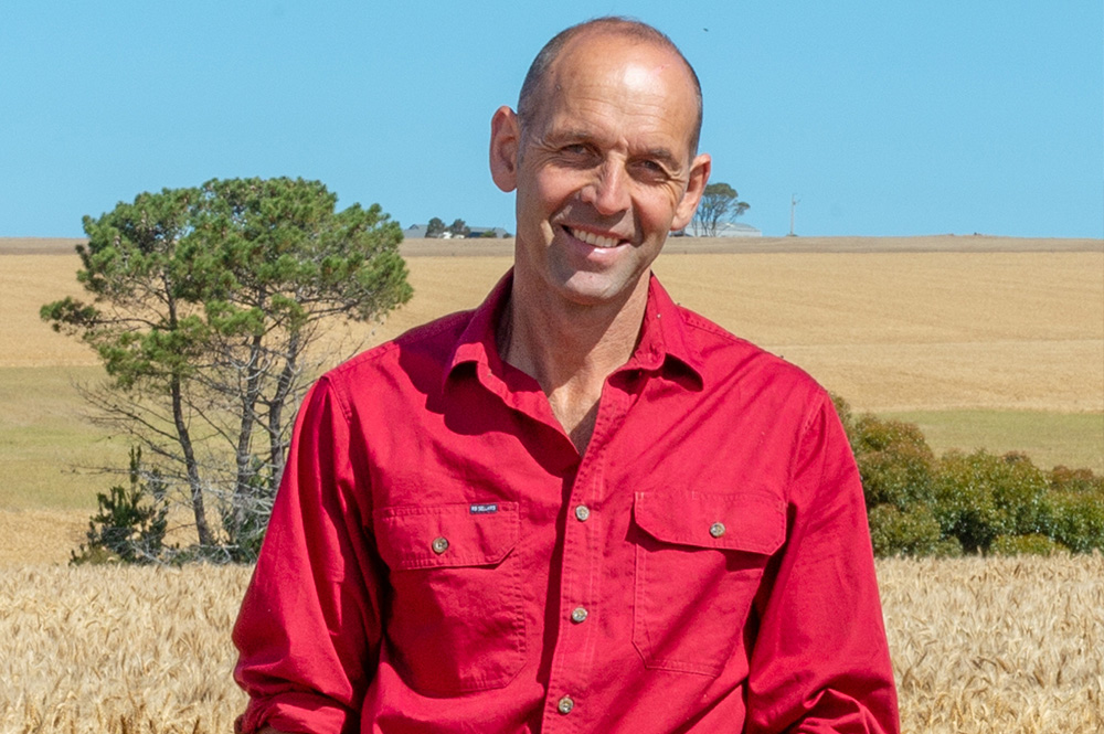 Farmer on property with wheat field and trees in background
