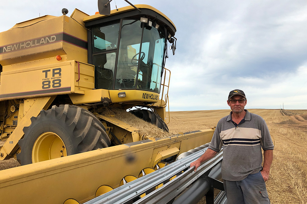 Farmer in cut wheat field next to machinery
