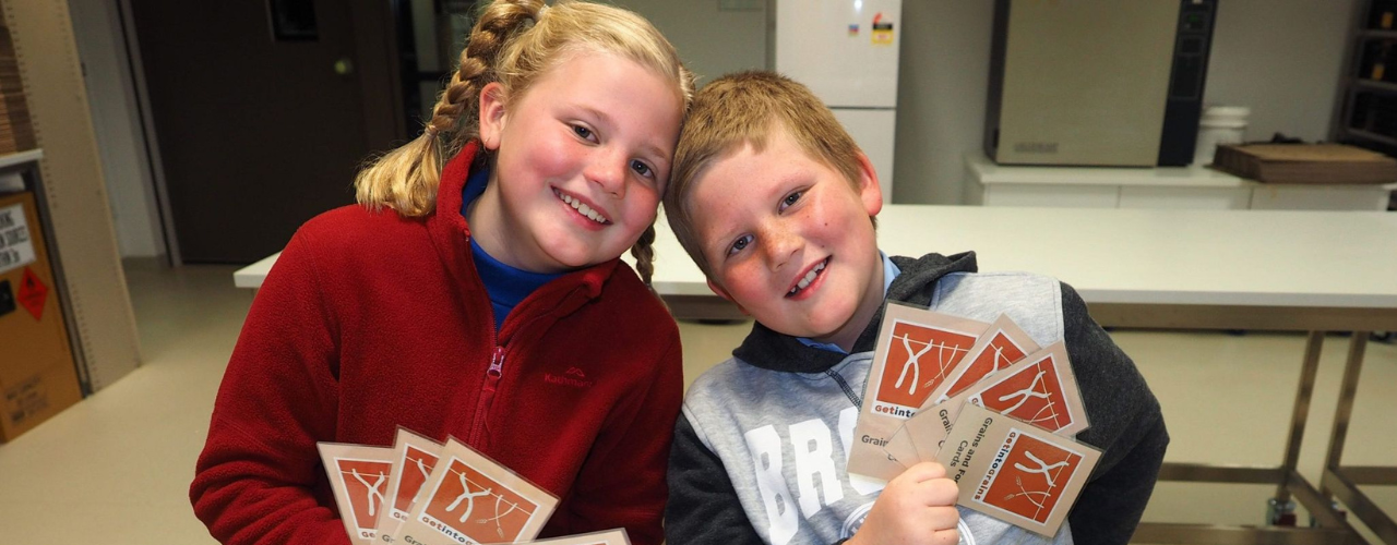 Image shows two students with course materials. Both are smiling.