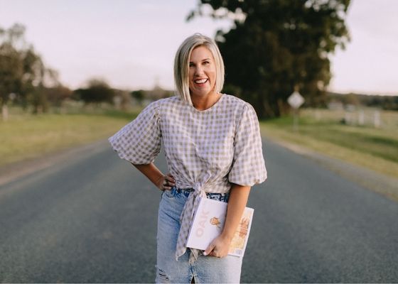 young blonde woman smiling on country road holding magazine 