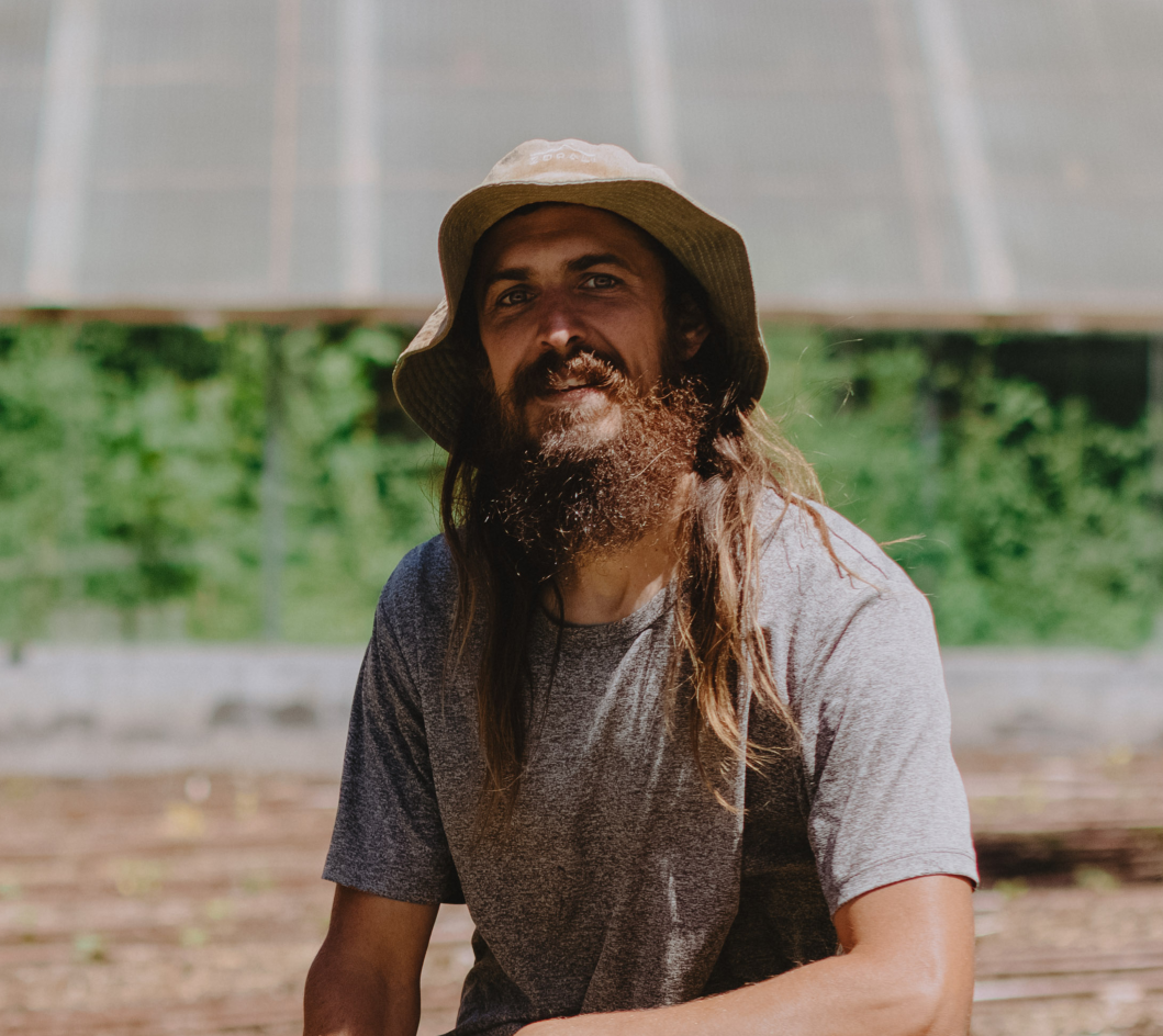 Joshua Williams kneeling in front of a garden.