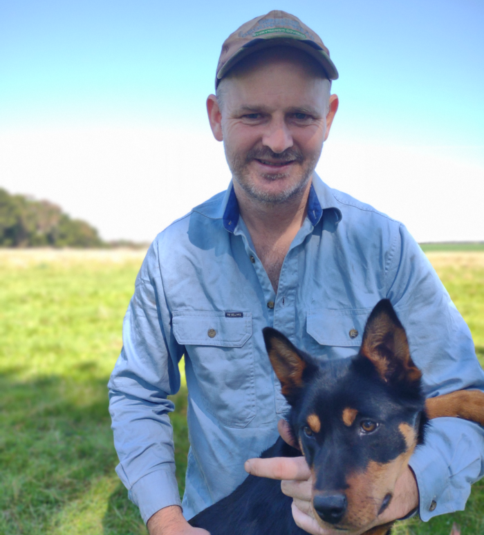 Nick Blandford holding a dog on an empty field.