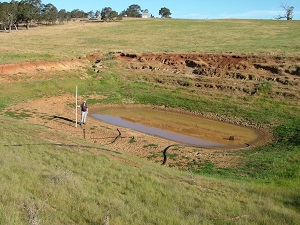 Farmer with a water depth gauge standing in a dry dam